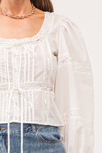 close up of blouse with pleating detailing and lace with white ribbon details